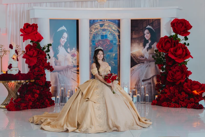 Quinceañera in a gold gown before a red rose backdrop